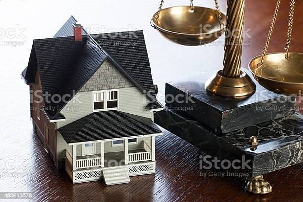 House and Scales of Justice on wood table. Concept mortgage, foreclosure, refinance