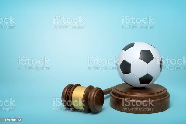 3d rendering of football on sounding block with judge gavel lying beside on light-blue background. Sport cause celebre. Football coach accused. Concussion lawsuit.